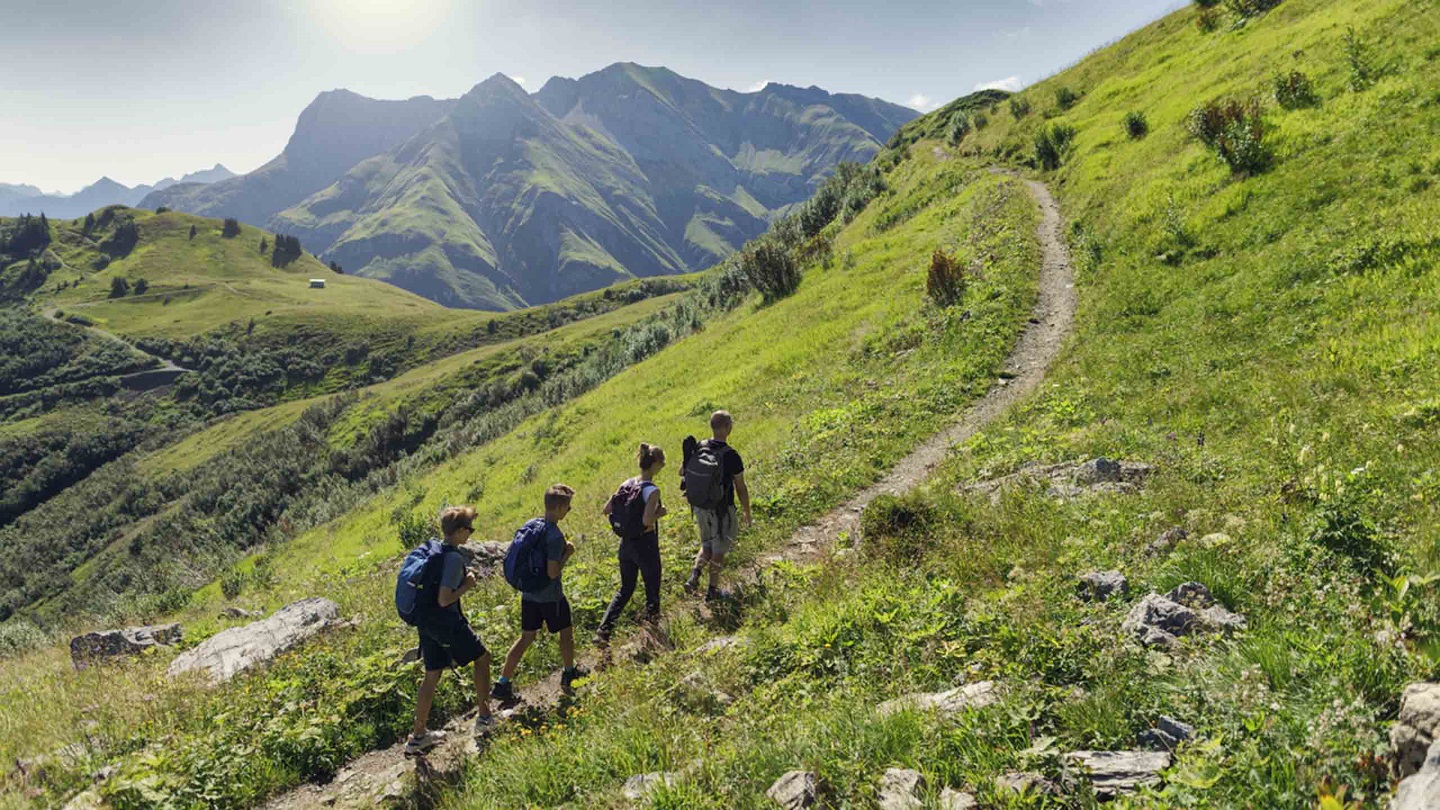 Father and teenage kids hiking in the Alps - Vorarlberg, Austria. They are walking on the footpath in the high mountains of Austria.Canon R5
